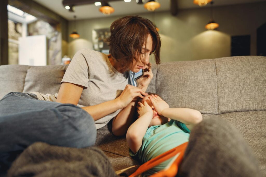 Alienação parental como denunciar - Robison Souza - Perito em Psicologia Forense A caring mother on the phone comforts her child on the sofa in a cozy living room.
