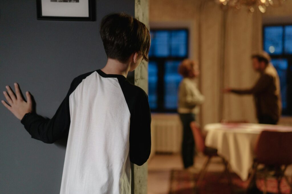 O que caracteriza alienação parental - Robison Souza - Perito em Psicologia Forense A child watches parents arguing from a doorway in a cozy home setting.