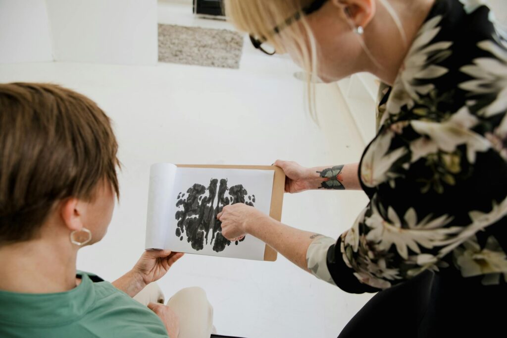 O que é avaliação psicossocial nr 35 - Robison Souza - Perito em Psicologia Forense Therapist discussing Rorschach inkblot test with a client in a therapy session.