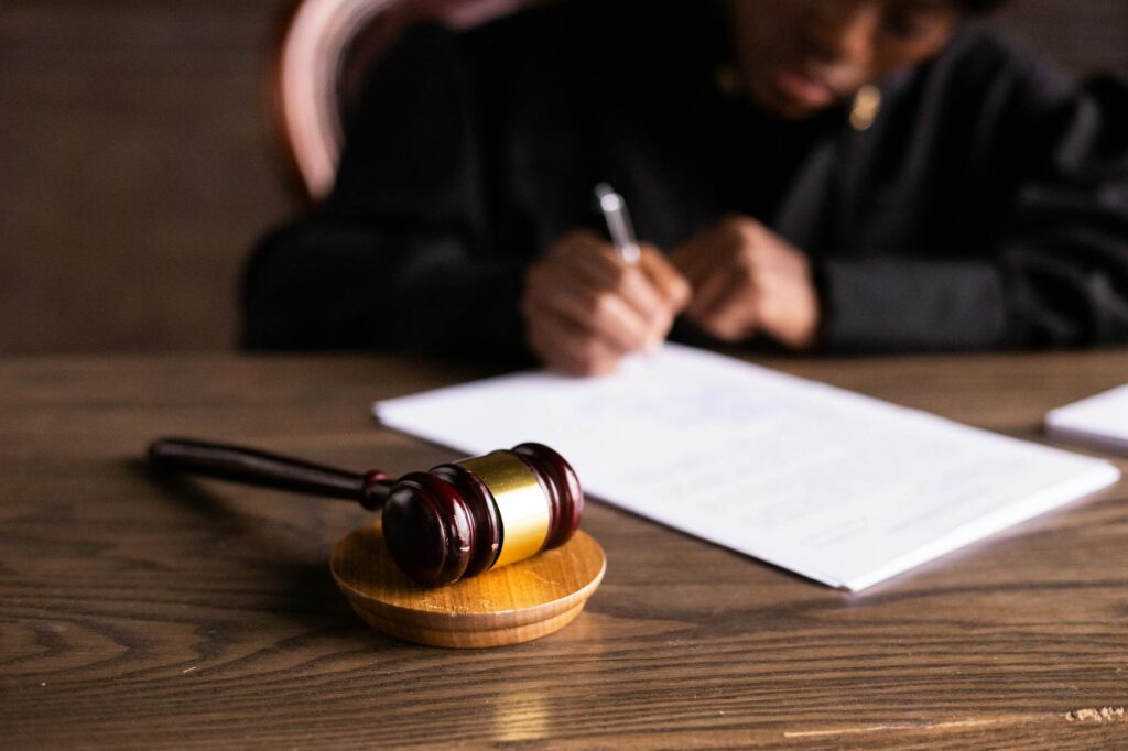 O que é guarda unilateral de filhos - Robison Souza - Perito em Psicologia Forense Judge signing documents at desk with focus on gavel, representing law and justice.