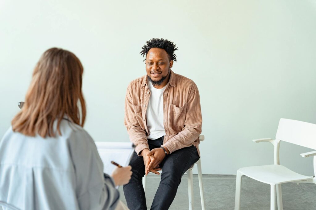 O que significa avaliação psicossocial - Robison Souza - Perito em Psicologia Forense A therapy session in a modern office setting with a counselor and a client engaged in conversation.