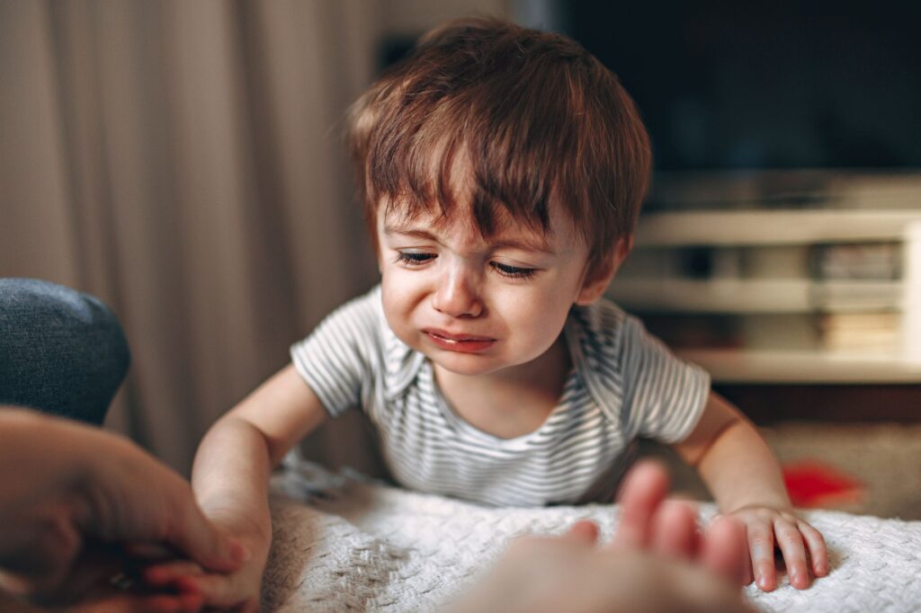 Qual o significado de alienação parental - Robison Souza - Perito em Psicologia Forense A close-up of a crying child indoors, displaying strong emotions and frustration.