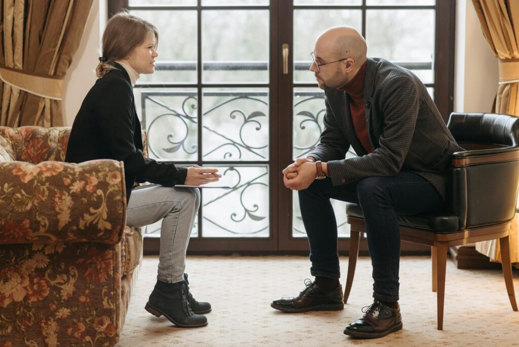 Quem faz avaliação psicossocial - Robison Souza - Perito em Psicologia Forense A thought-provoking therapy session with therapist and client discussing in a cozy room.