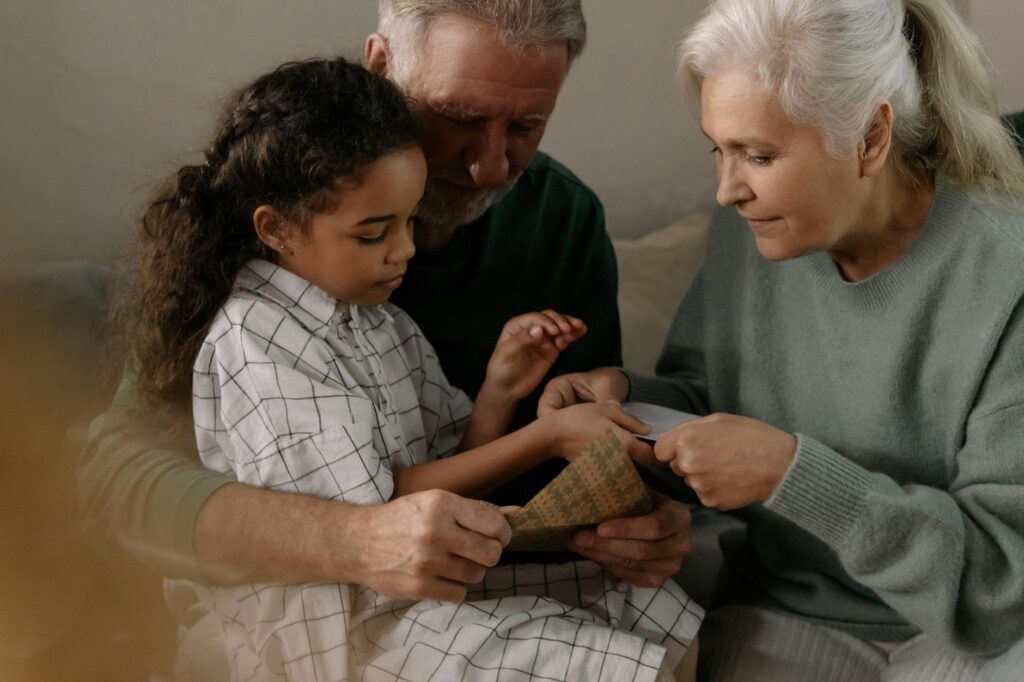 O que é alienação parental em relação aos avós - Robison Souza - Perito em Psicologia Forense Grandparents bonding with their granddaughter over a cherished family photo indoors.