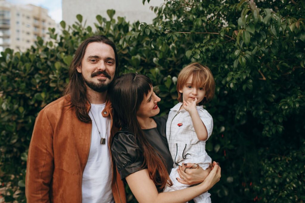 Quando ocorre a alienação parental - Robison Souza - Perito em Psicologia Forense A joyful family stands together outdoors against a green leafy backdrop.